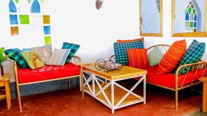 A cozy room with two red sofas, a wooden coffee table, and a small side table. - Cabin in the Farm - Peach (Nakuru)