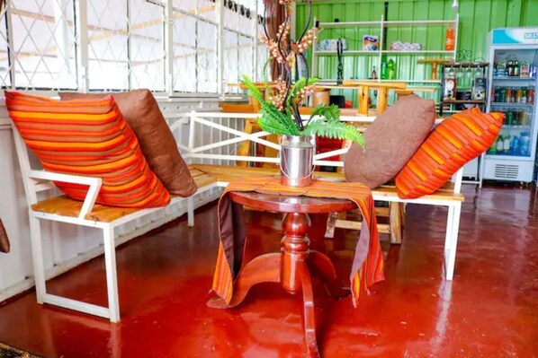 A room with a red floor, white furniture, and a green wall. There is a table with a vase of flowers and striped cushions.