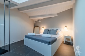 Een moderne slaapkamer met een groot bed, nachtlampen en een klein nachtkastje.