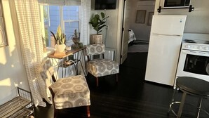A compact kitchen with a refrigerator, stove, and microwave. There is a dining area with a table and chairs, and a window providing natural light.