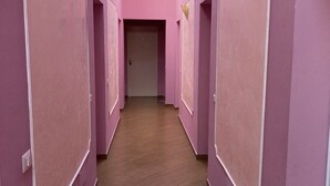 En lång korridor med rosa väggar och trägolv.