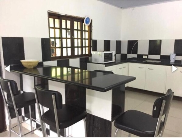 Een koelkast, kookgerei, borden en bestek, een eettafel