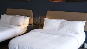 A hotel room with two beds, a nightstand, a lamp, and two wall-mounted artworks depicting night scenes. - Motolodge (Pendleton)