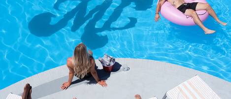 Un espace aménagé au bord de la piscine, avec des chaises longues et un seau rempli de boissons.
