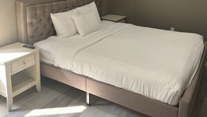 A bedroom with a bed, nightstands, and an air conditioning unit.