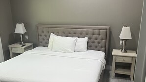 A neatly made bed with white linens, two bedside tables with lamps, and a tufted headboard.