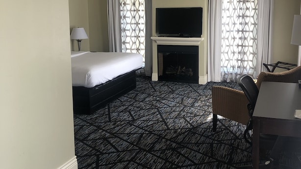 A hotel room with a bed, a TV, a fireplace, and a seating area. - Niagara Crossing Hotel and Spa King Room (Lewiston)