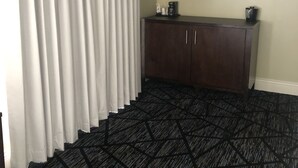 A room with a patterned carpet, a dark wooden cabinet, and a framed picture on the wall. - Niagara Crossing Hotel and Spa King Room (Lewiston)