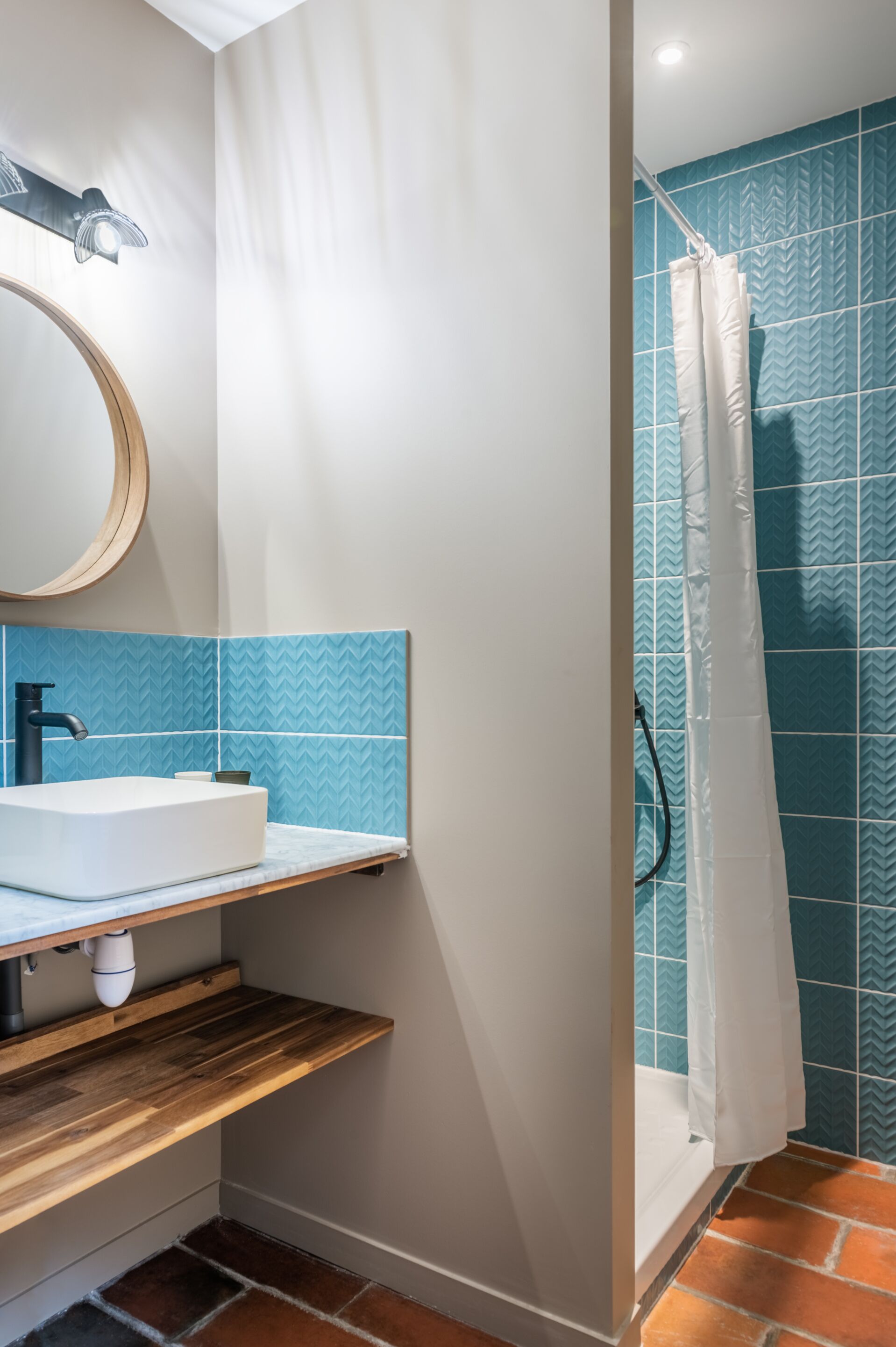 Une salle de bain avec un lavabo blanc, un miroir et des carreaux bleus à motifs.