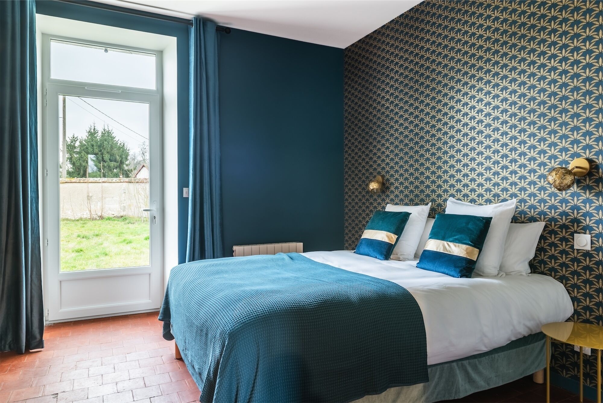 Une chambre à coucher avec un lit, une fenêtre et un mur décoré d’un motif.