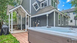 A hot tub on a wooden deck, a covered porch, and a house with a dark exterior. - Home in Downtown Breck w/ private hot tub, fireplace, and walkable to Main St (Breckenridge)
