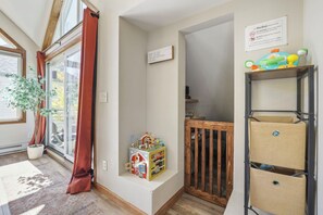 A room with a large window, a potted plant, a toy box, a wooden gate, and a shelf with storage baskets. - Home in Downtown Breck w/ private hot tub, fireplace, and walkable to Main St (Breckenridge)