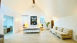 Une chambre spacieuse avec un grand lit, un canapé et une fenêtre donnant sur un beau paysage.