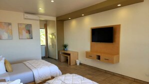 A hotel room with two beds, a TV mounted on the wall, and a small table with a plant. - Hotel Paraíso Las Palmas (Ensenada)