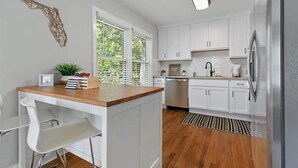 Een moderne keuken met witte kasten, een houten aanrecht en een roestvrijstalen koelkast.