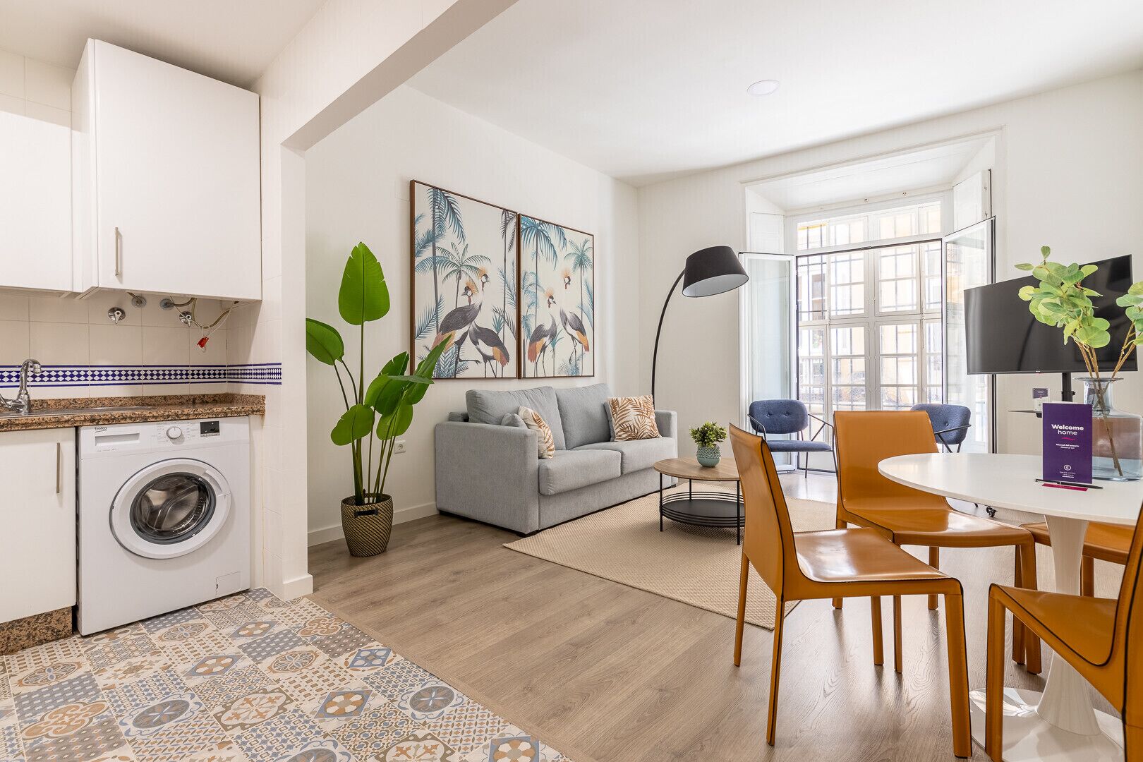 A modern living room with a grey sofa, a coffee table, and a dining area with wooden chairs.