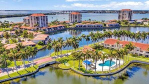 A resort with multiple buildings, a central pool, and palm trees.