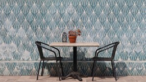 A table with two chairs and a potted plant against a patterned wall. - Casa Bruna Luxury Lofts (Tampico)