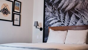A bedroom with a bed, a wall-mounted lamp, framed artwork, and a ceiling light fixture. - Casa Bruna Luxury Lofts (Tampico)