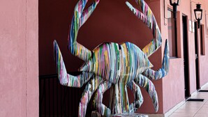 A colorful crab sculpture on a tiled floor, with a pink wall and black railings in the background. - Casa Bruna Luxury Lofts (Tampico)