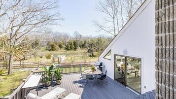 Relax on the spacious deck with a lounge chair or dine at the outdoor table amidst lush greenery and a serene view.