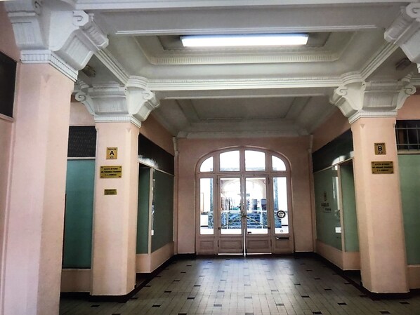 A hallway with a large arched doorway, columns, and a tiled floor.