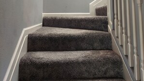 Un escalier dont les marches sont recouvertes de moquette et sur lequel on peut lire, sur le mur, l’inscription « BIENVENUE ».