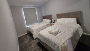 Une chambre avec deux lits, une fenêtre et un luminaire au plafond.