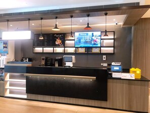 A modern reception desk with a digital screen, a coffee machine, and a payment terminal. - Hanting Hotel (Kuytun)