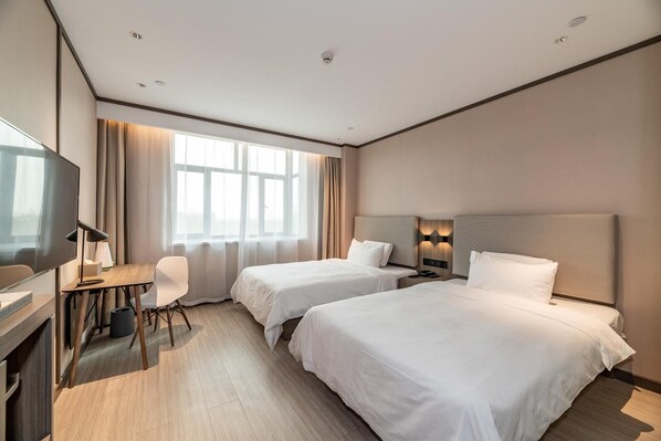 A hotel room with two beds, a desk with a chair, a television, and a large window with curtains. - Hanting Hotel (Kuytun)