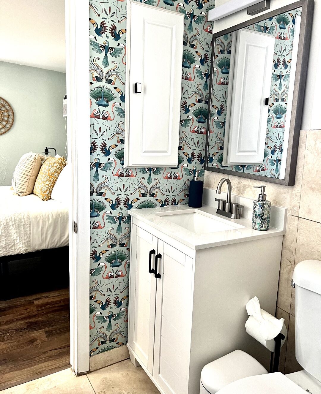 A bathroom with a white sink, a mirror, and a toilet. The walls have a floral wallpaper pattern.