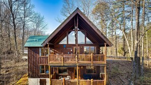 A two-story log cabin with a balcony, surrounded by trees. - Alpine Splendor Cabin Mountain Views Hot Tub (Sevierville)