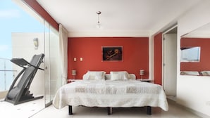 A bedroom with a bed, a treadmill, and a large window.
