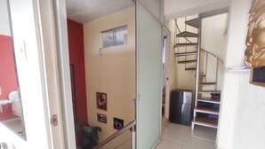 A hallway with a staircase, a refrigerator, and a door leading to another room.