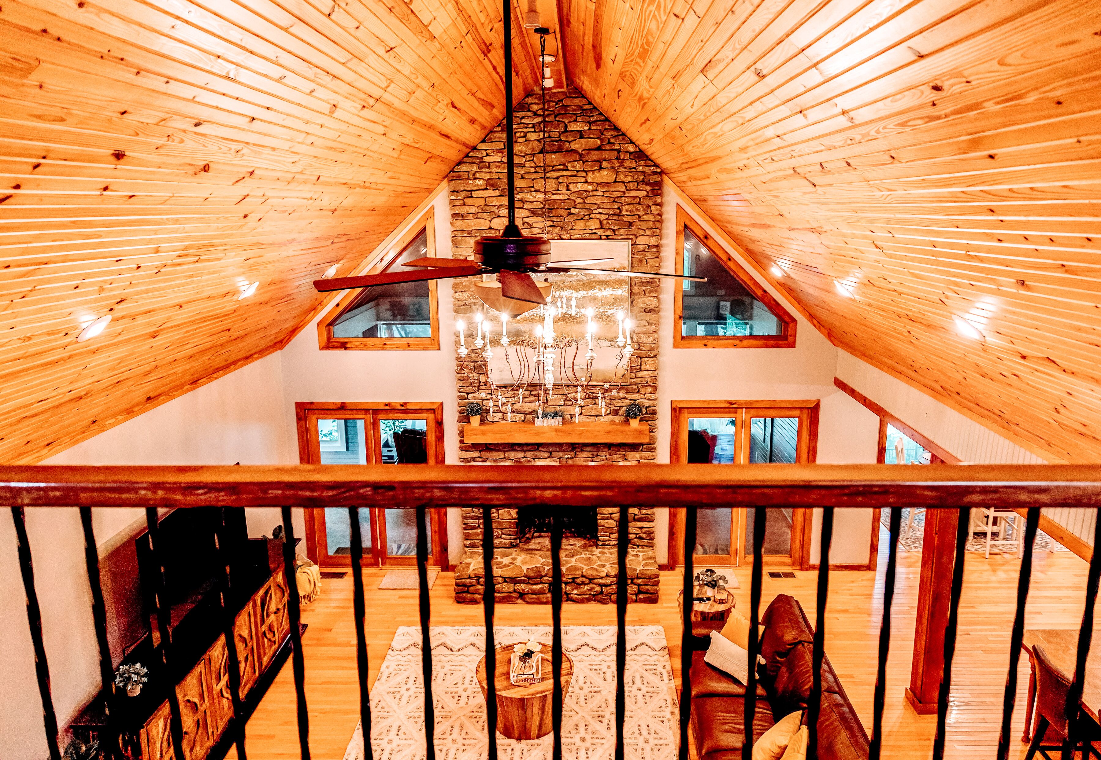 Un loft spacieux avec de hauts plafonds, des poutres en bois, une cheminée en pierre et une grande fenêtre.