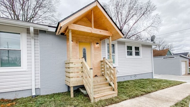 Eenlaags huis met een houten veranda en een kleine trap naar de voordeur.