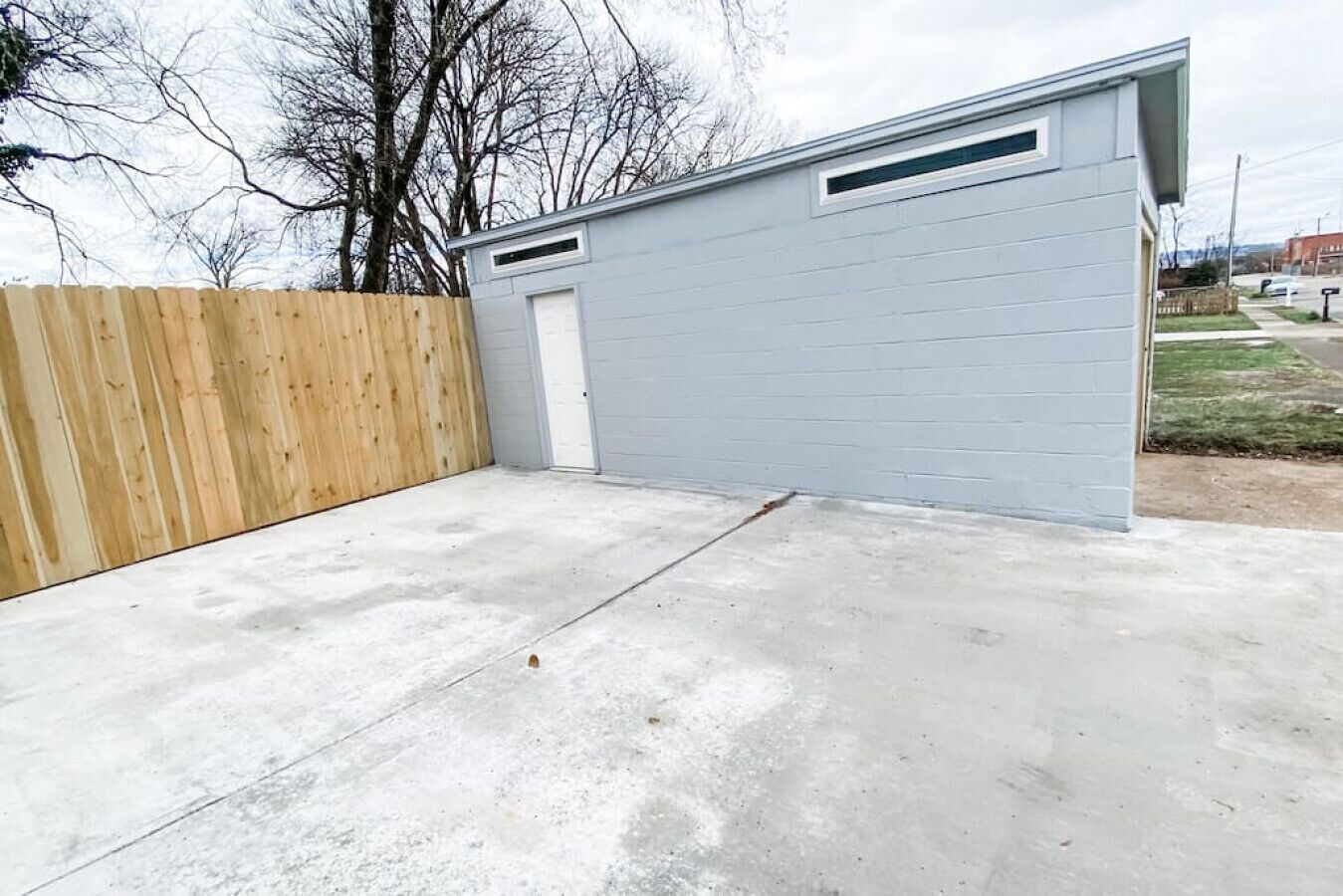 Un garage avec un sol en béton et une clôture en bois.