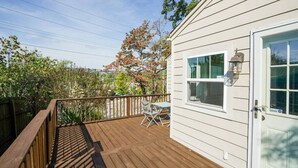 Eine Holzterrasse mit Tisch und Stühlen, eine weiße Tür und ein Fenster mit einer Laterne.