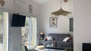 Una sala de estar moderna con un sofá, una televisión y un comedor con una mesa de madera.