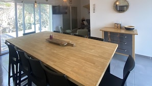Un comedor moderno con una mesa de madera, sillas negras e lámparas colgantes.