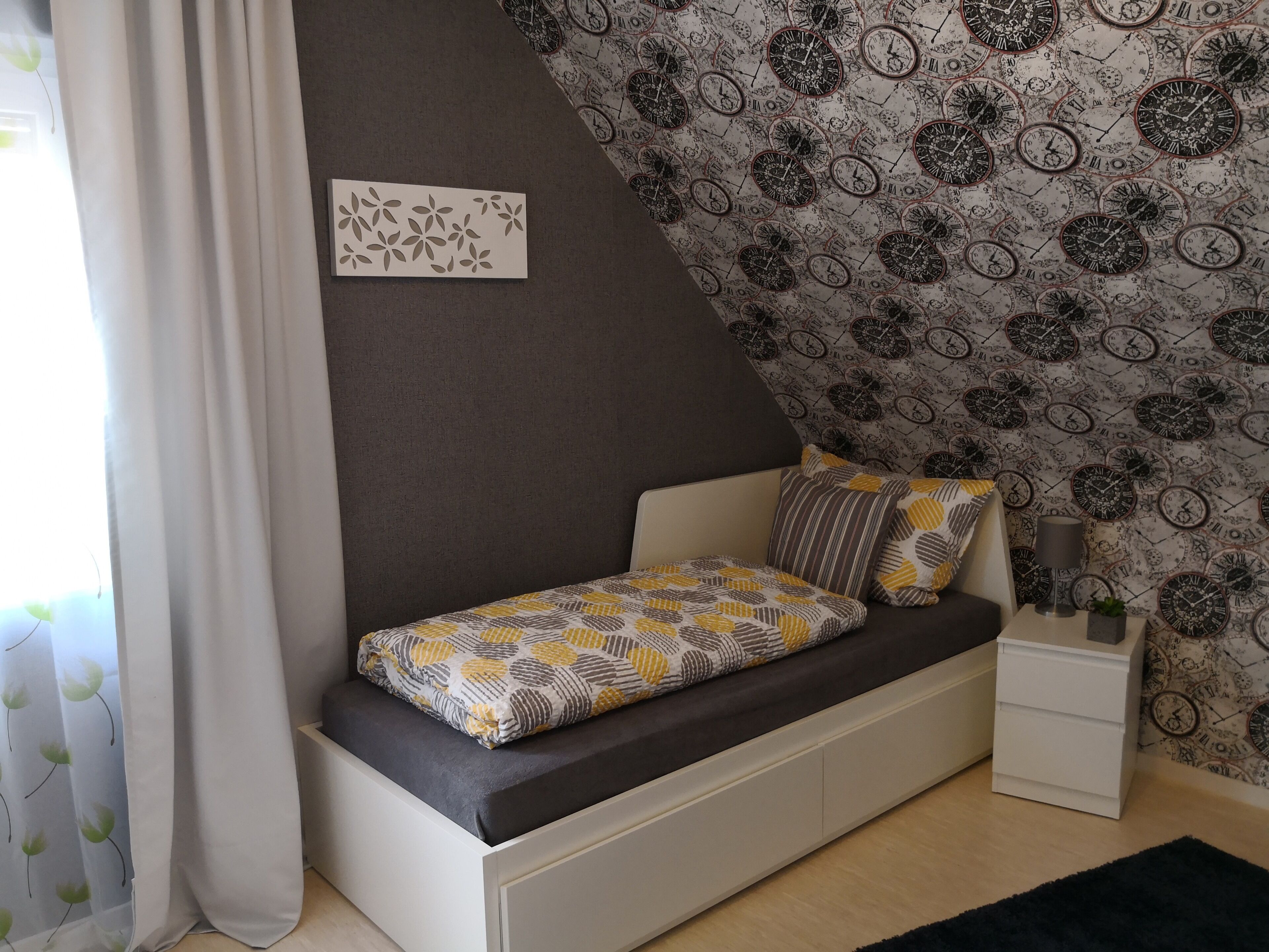 A modern bedroom with a built-in bed, a small bedside table, and a wall clock.