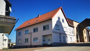 Un bâtiment à deux étages, doté d’un toit recouvert de tuiles rouges, de nombreuses fenêtres et d’une enseigne visible donnant sur la rue.