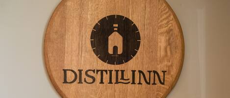 Un letrero de madera circular con un logotipo y la palabra 'DISTILLINN'.