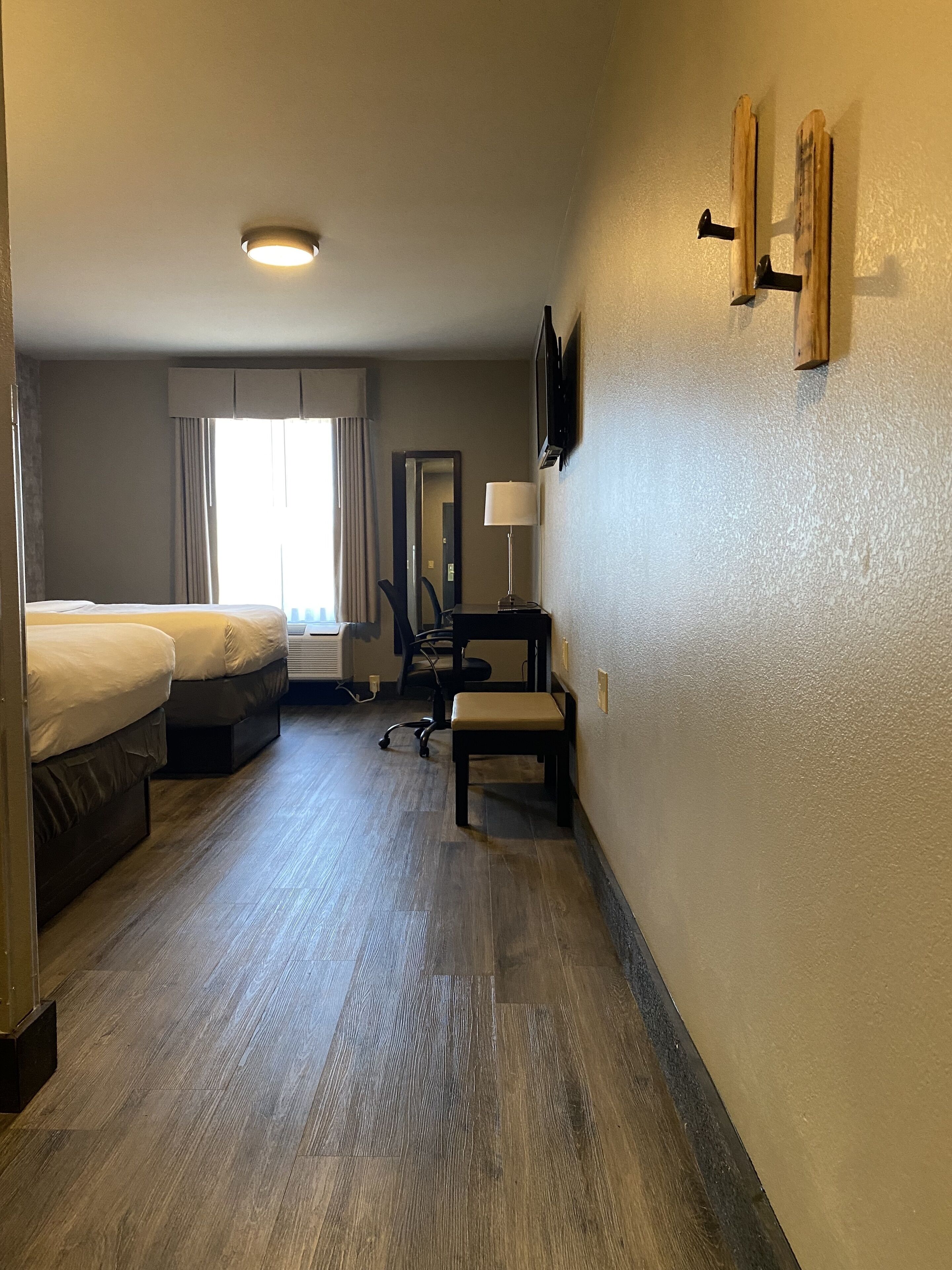 Ein Hotelzimmer mit einem Bett, einem Schreibtisch, einem Stuhl, einem Spiegel und einem Fernseher.