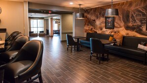 A modern hotel lobby with leather seating, a bar area, and a mural on the wall. - Distill-Inn (Bardstown)
