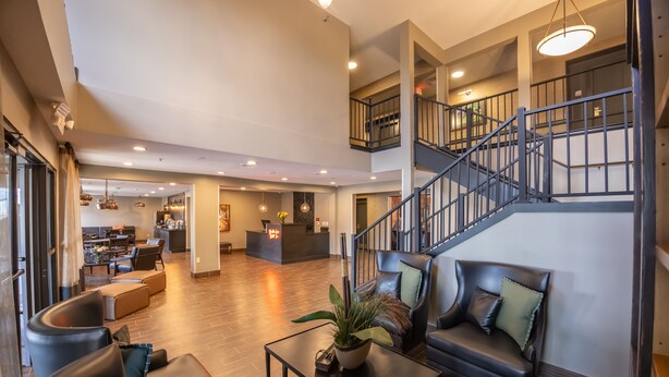 A spacious lobby with leather seating, a reception desk, and a staircase. - Distill-Inn (Bardstown)
