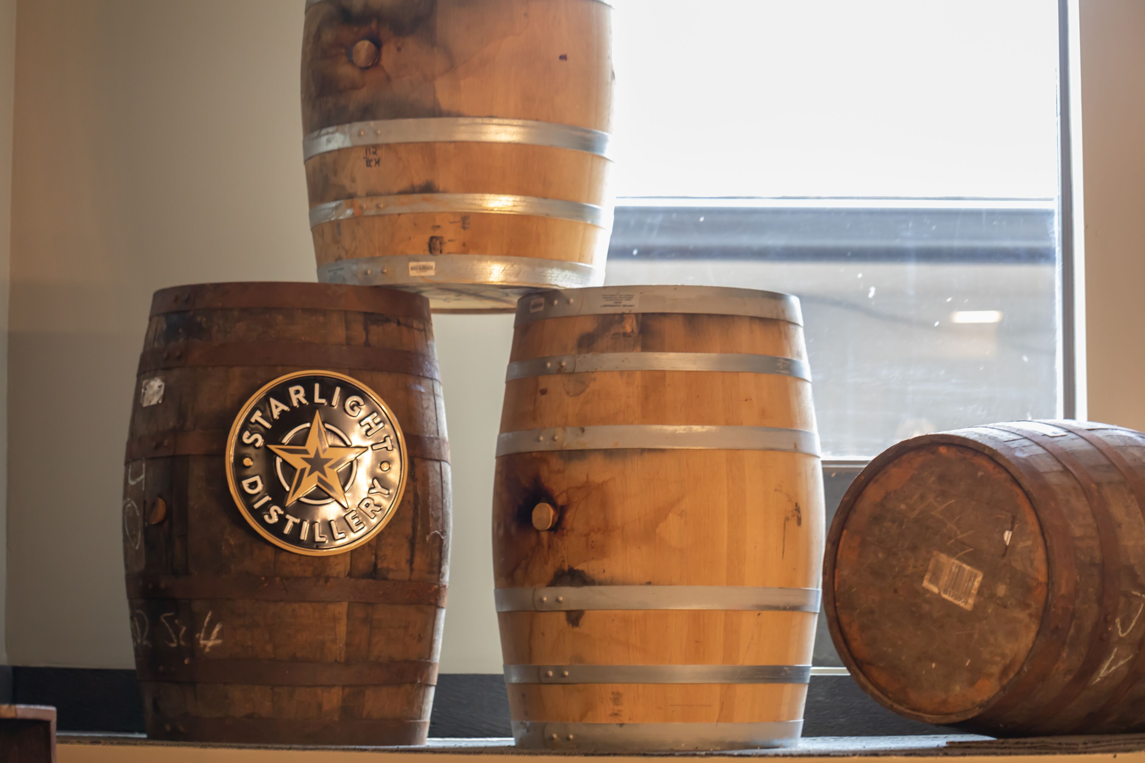 Tres barriles de madera con bandas metálicas y una etiqueta que dice 'Starlight Distillery'.