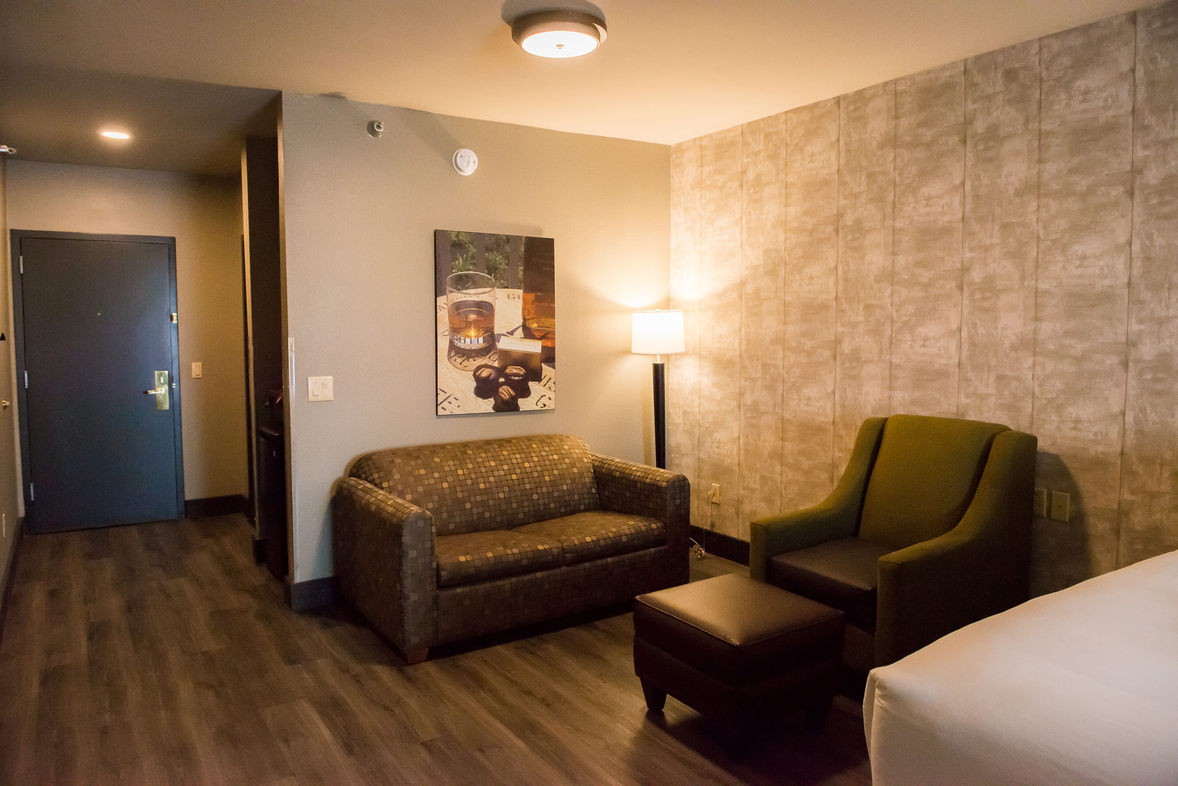 Quarto de hotel com sofá, poltrona e cama.