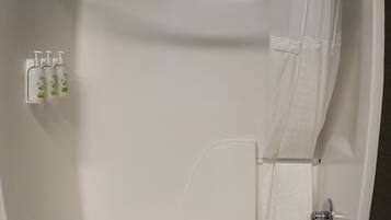 A white bathtub with a shower curtain, a towel, and three bottles of Dove body wash.