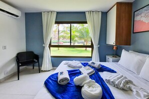 A hotel room with a bed, a chair, a window with curtains, a nightstand, and a lamp. - VG Sun Cumbuco Luxo 2 quartos 6 pessoas By DM Apartments (Caucaia)